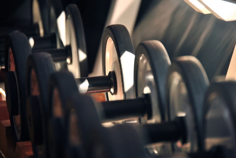 Rack of black dumbbells in a dim gym