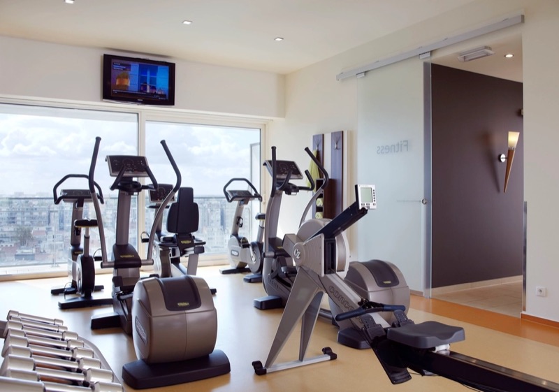 Small gym with cardio machines beside a large window