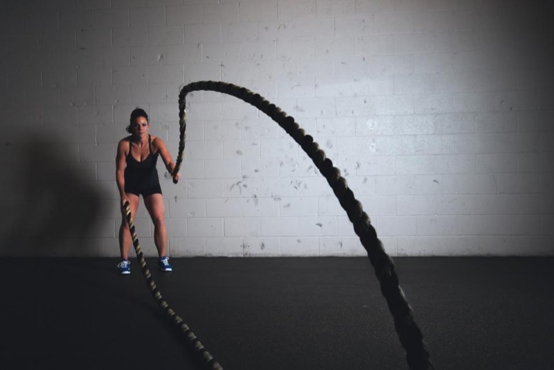Coach training with battle ropes in a dark studio