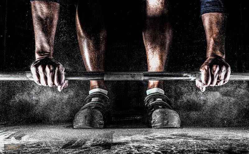 Hands gripping a loaded barbell before a lift